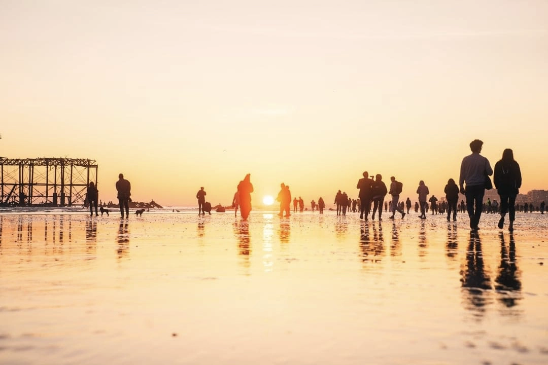 People walking on a beach at sunset